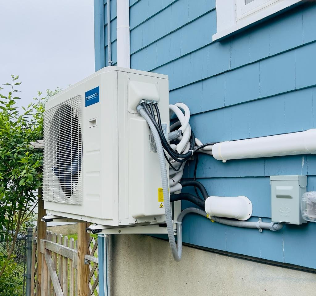Ductless mini-split HVAC unit installed on the side of a blue house in New Hampshire
